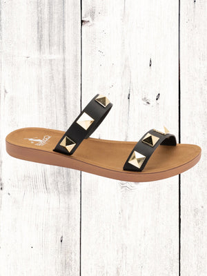 A black flat sandal with gold studs, featuring a comfortable fit and a brown sole.
