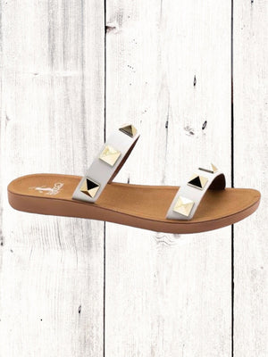 A black flat sandal with gold studs, featuring a comfortable fit and a brown sole.