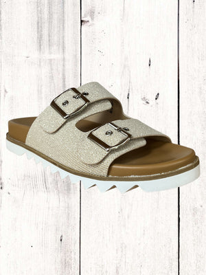 An image featuring a pair of black Corkys Dash sandals with adjustable buckles and a flat sole, displayed against a wooden background.
