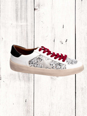 A sneaker with white sequins and star detailing, red laces, and a beige sole.
