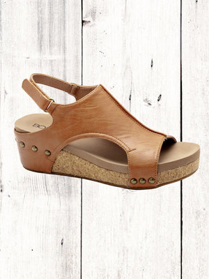 A black Corkys Volta II wedge sandal with a faux leather upper and cork wedge heel, featuring a hook and loop closure and studs on the heel.