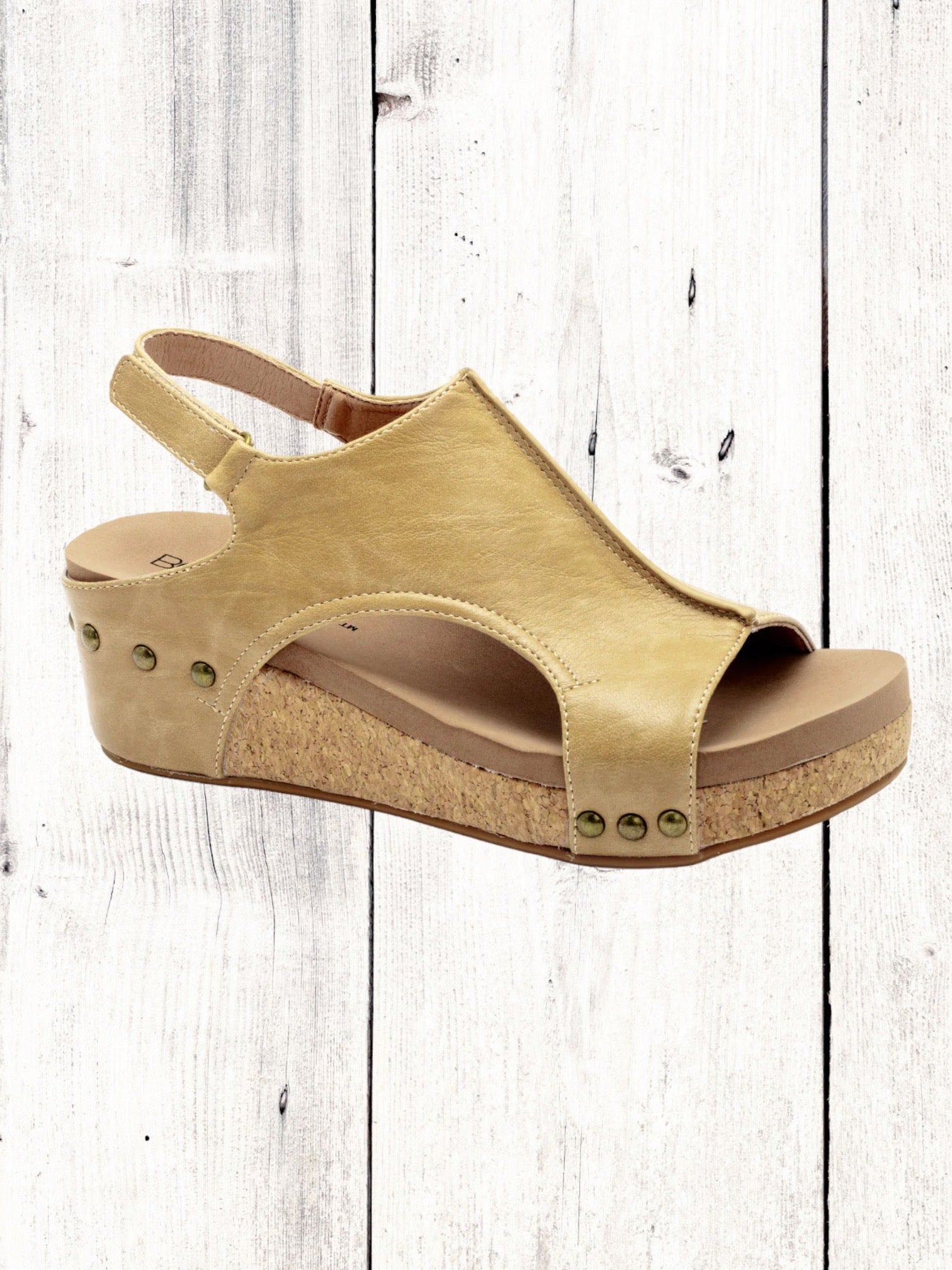 A black Corkys Volta II wedge sandal with a faux leather upper and cork wedge heel, featuring a hook and loop closure and studs on the heel.