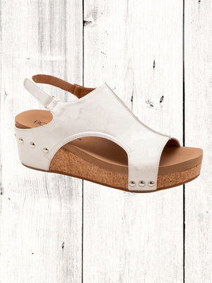 A black Corkys Volta II wedge sandal with a faux leather upper and cork wedge heel, featuring a hook and loop closure and studs on the heel.