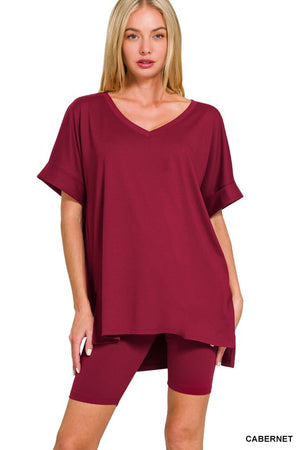 Woman wearing a cabernet-colored oversized t-shirt and shorts set on a white background