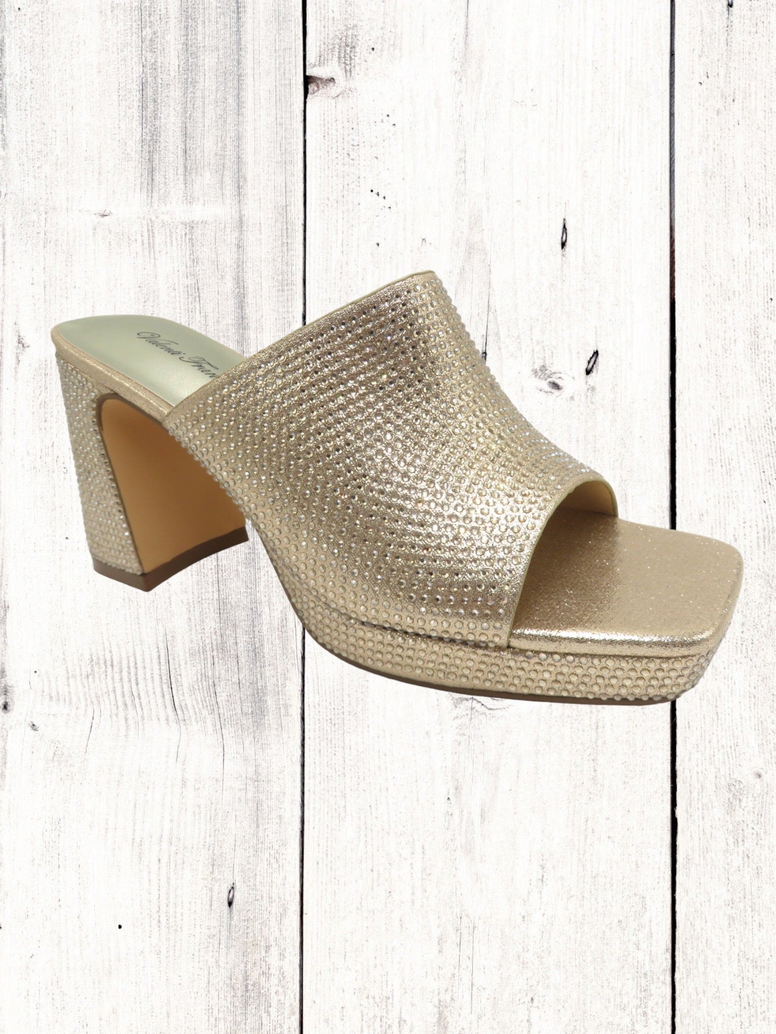 A gold-colored Pierre Dumas Lois-2 heel with a single band, square open toe, and a tall block heel on a wooden floor.