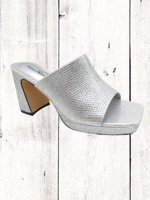 A gold-colored Pierre Dumas Lois-2 heel with a single band, square open toe, and a tall block heel on a wooden floor.