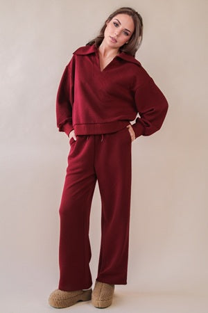 Woman wearing a burgundy outfit against a plain background