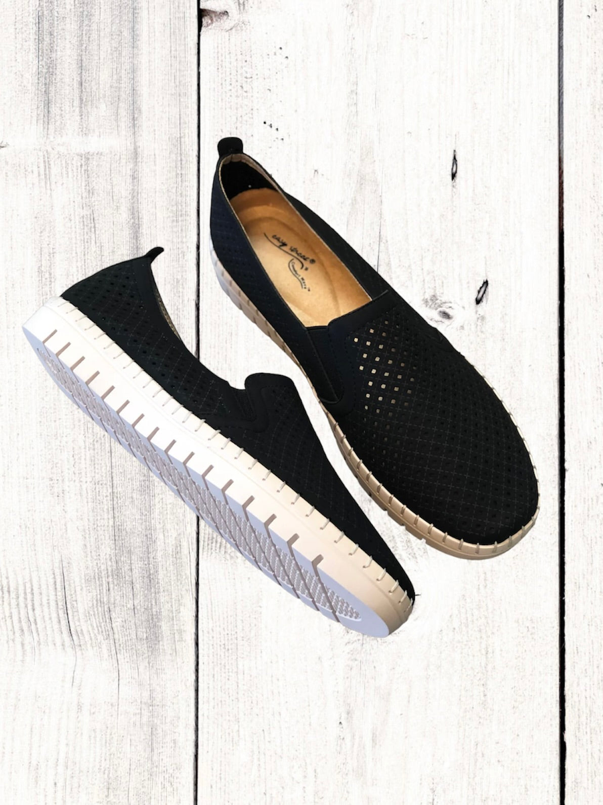 A pair of black Easy Street brand sneakers with a flexible outsole, featuring a perfed upper with twin gores for stretch fit, and an insole with a light-colored footbed.