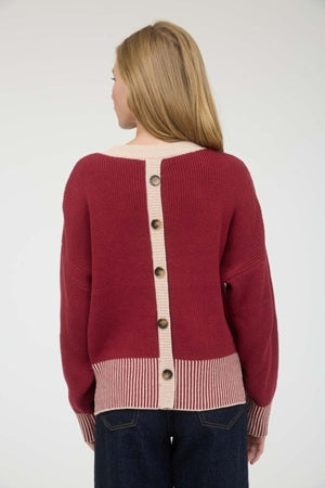 Red sweater with button details on a plain background
