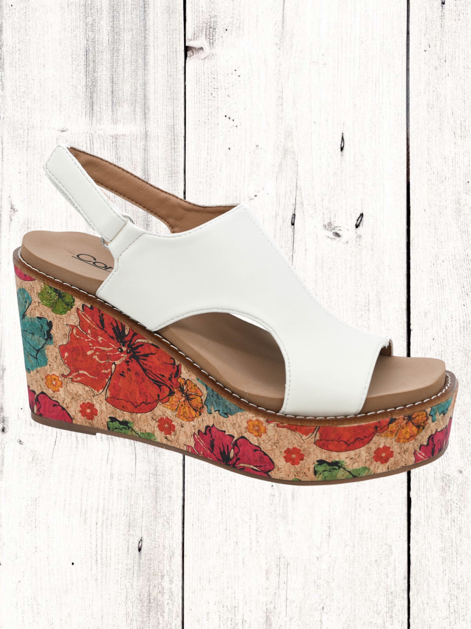 A white faux leather wedge sandal with a floral pattern on the platform and a braided wedge heel.