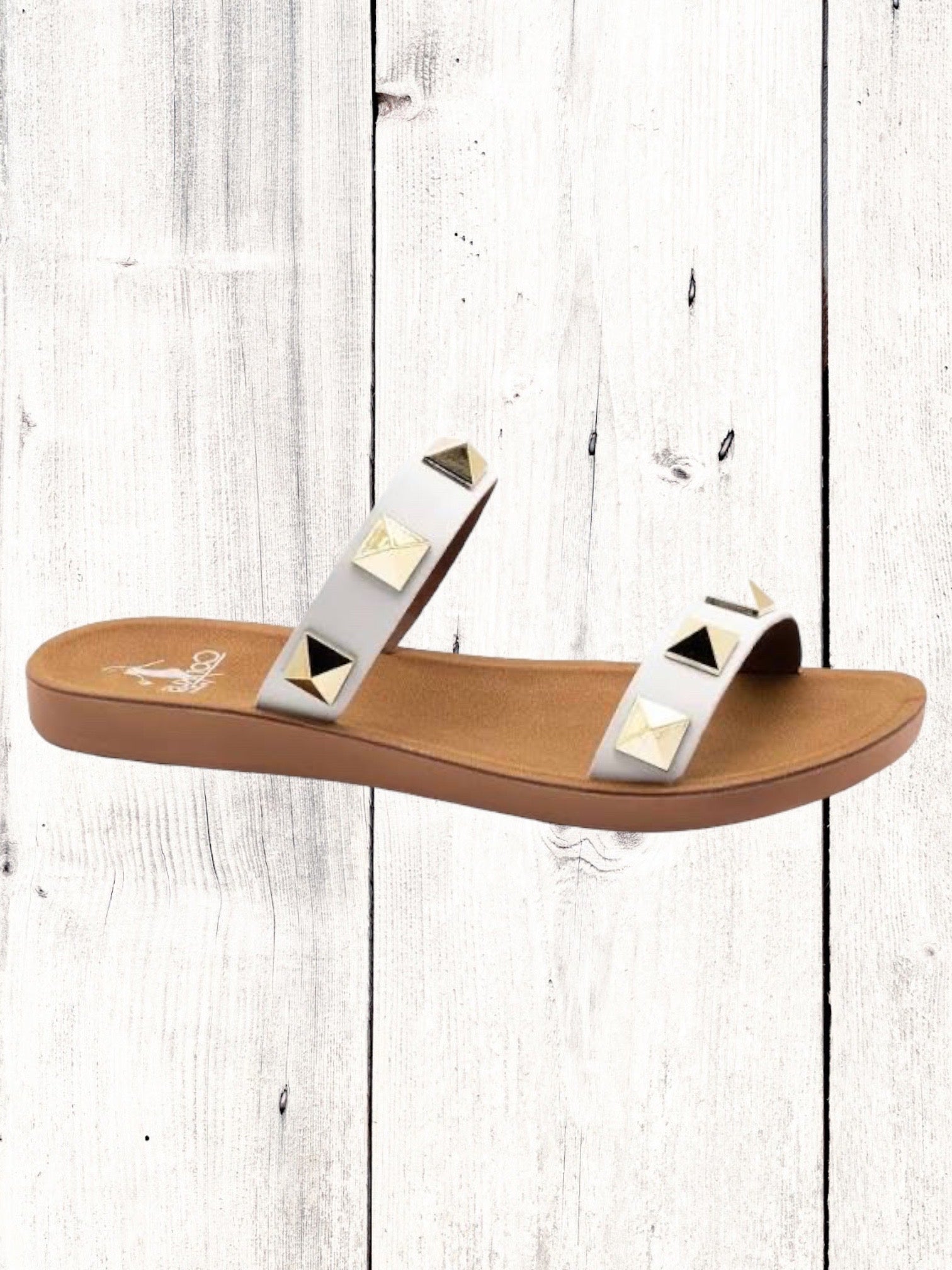 A black flat sandal with gold studs, featuring a comfortable fit and a brown sole.