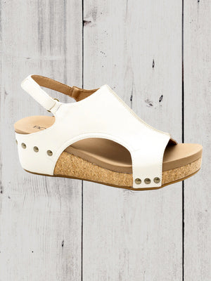 A black Corkys Volta II wedge sandal with a faux leather upper and cork wedge heel, featuring a hook and loop closure and studs on the heel.