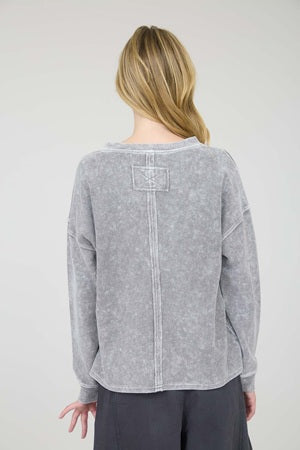 Person wearing a gray sweater with a visible brand logo on a white background