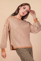 Woman wearing a beige sweater with a leopard print bottom on a beige background