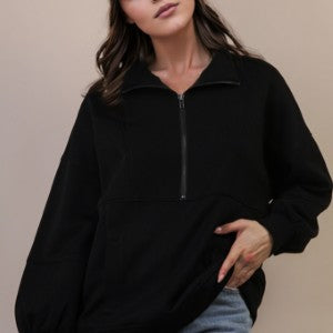 Person wearing a black zip-up sweatshirt against a neutral background