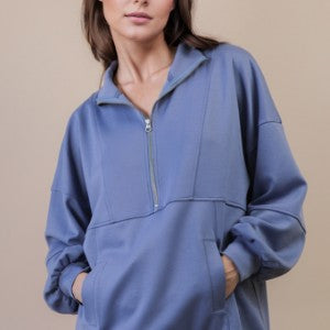 Woman wearing a blue pullover with a zipper on a beige background