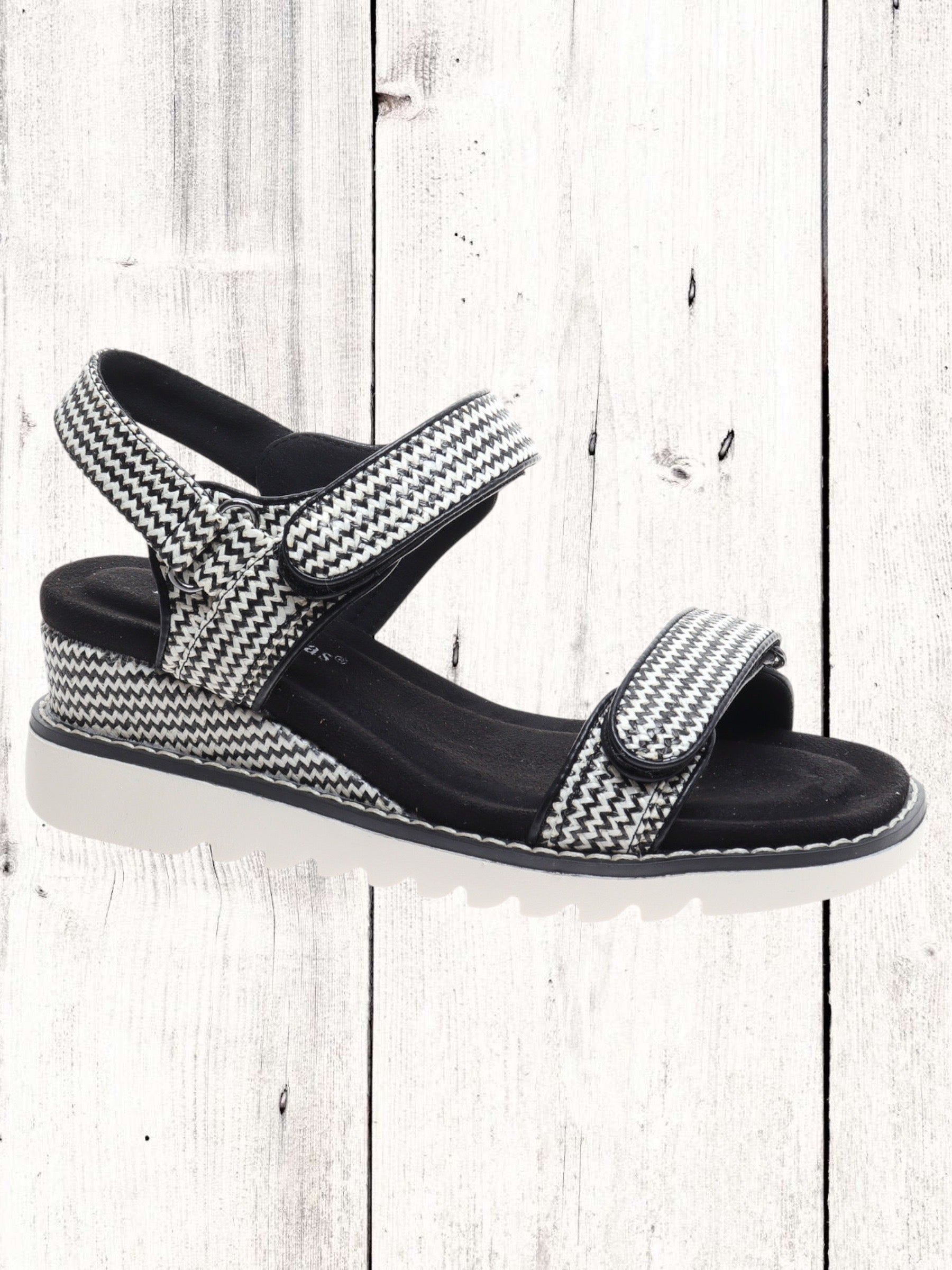 A black and white geometric patterned wedge sandal with two Velcro straps and a cushioned insole.