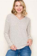 Woman wearing a striped long-sleeve top and blue jeans against a white background