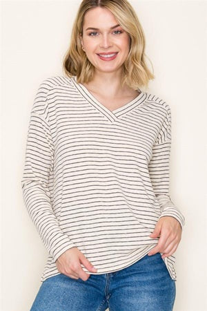 Woman wearing a striped long-sleeve top and blue jeans against a white background