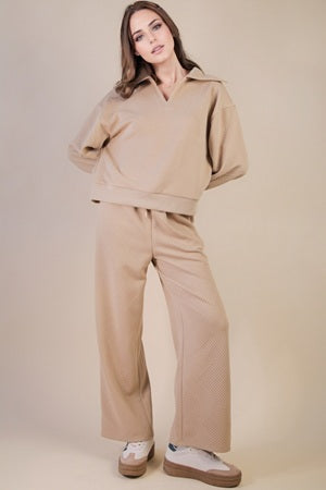 Woman wearing a beige tracksuit against a plain background