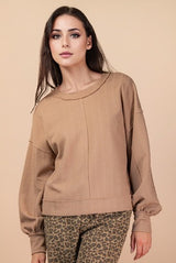 Woman wearing a beige sweater and leopard print pants on a beige background
