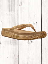 A pair of beige flip flops with a woven raffia upper and a low platform sole.