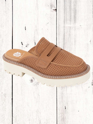 A Yellow Box Sherlyn Mule featuring a perforated upper, chunky padded heel, and a lug outsole, set against a wooden backdrop.