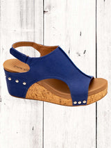 Blue sandal with cork wedge sole on a white wooden background
