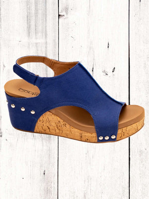Blue sandal with cork wedge sole on a white wooden background