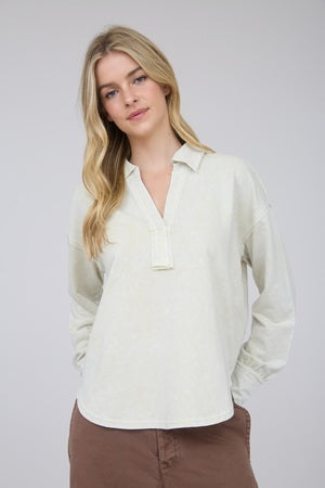 Woman wearing a light-colored shirt with long sleeves against a plain background