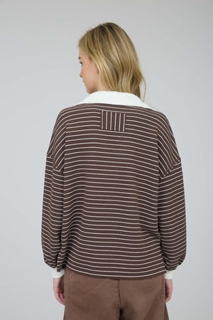 Person wearing a brown and white striped sweater with a plain background