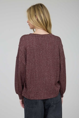 Person wearing a maroon sweater with a plain background