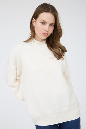 Woman wearing a cream sweater against a white background